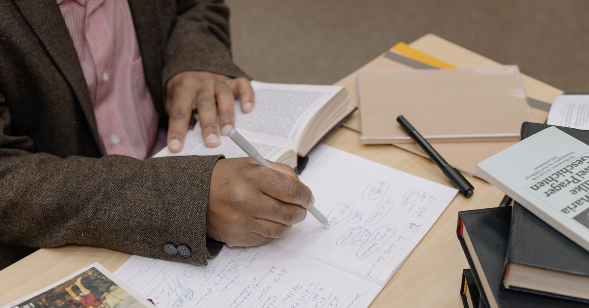A researcher writing a cover letter at a university desk