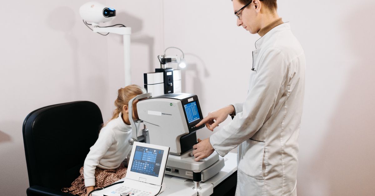 An optometrist examining a patient's eyes using specialist clinical equipment