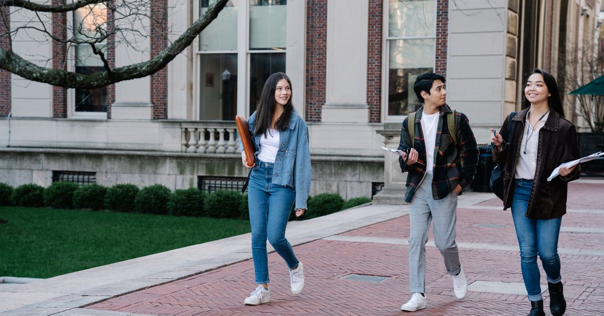 Students walking across a UK university campus on a bright day